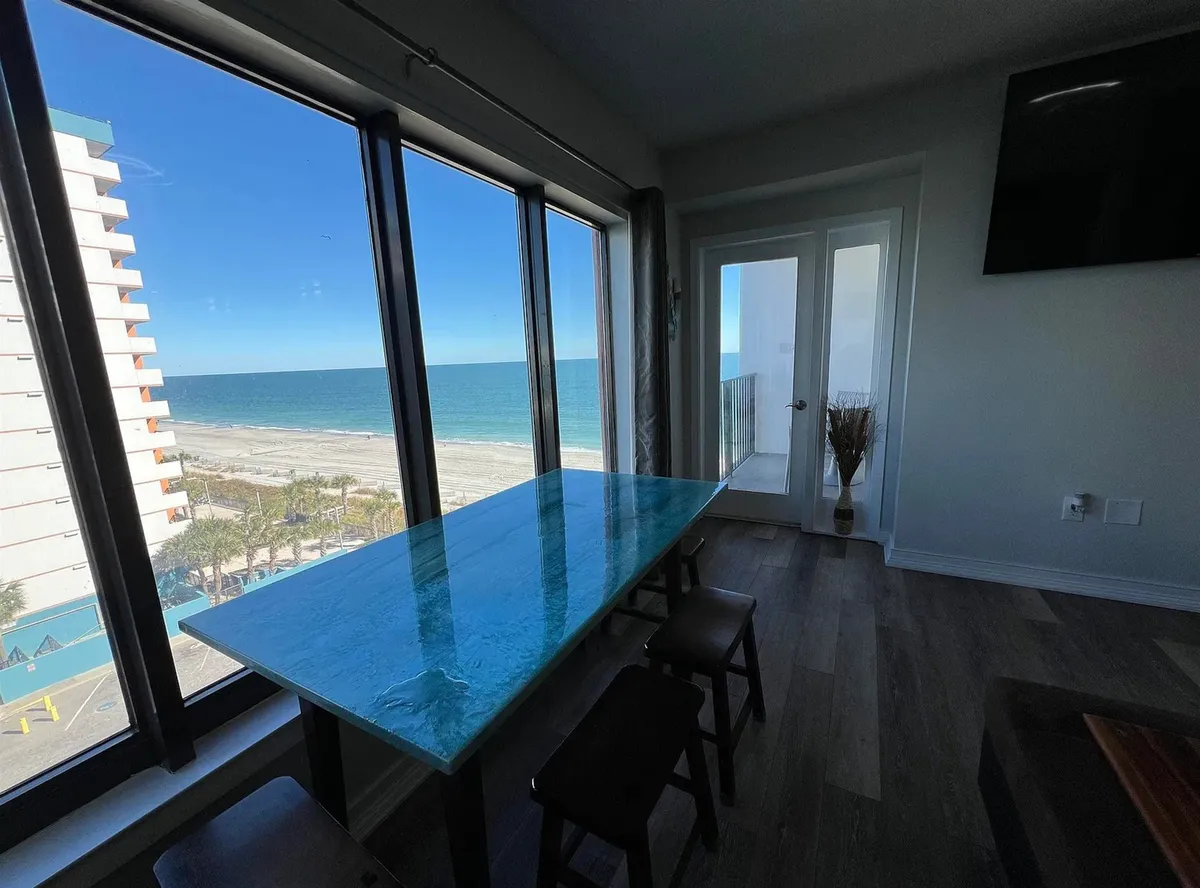 A glass dining table set beside a sliding glass door, offering panoramic ocean views. The relaxed, tranquil atmosphere makes this the perfect spot for sunrise breakfasts or memorable family dinners with an ocean backdrop.