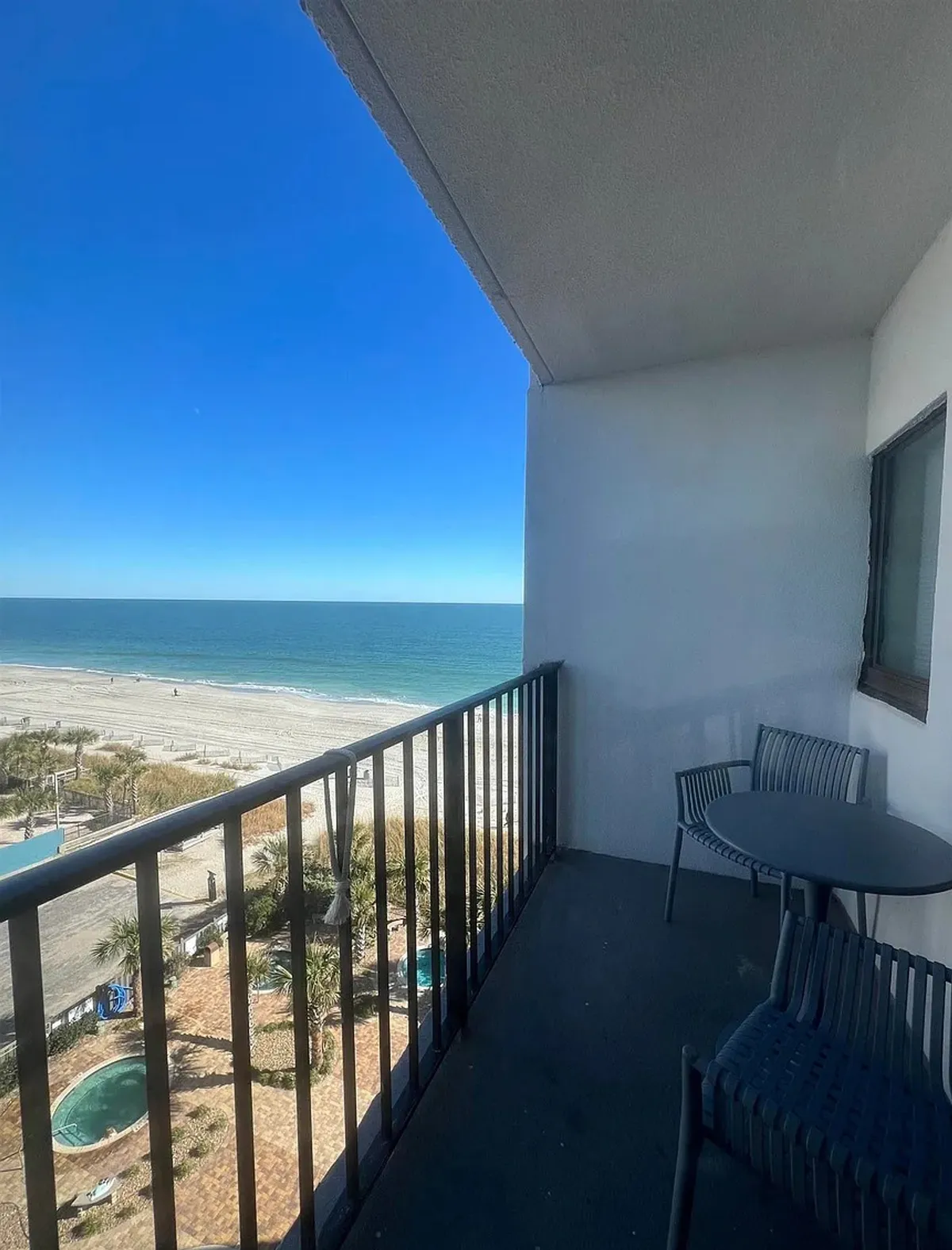 The image showcases a peaceful private balcony with comfortable patio furniture, overlooking the endless blue expanse of the Atlantic Ocean. Sunlight sparkles on the water, and the inviting outdoor space promises relaxation with breathtaking sunrises and gentle sea breezes.