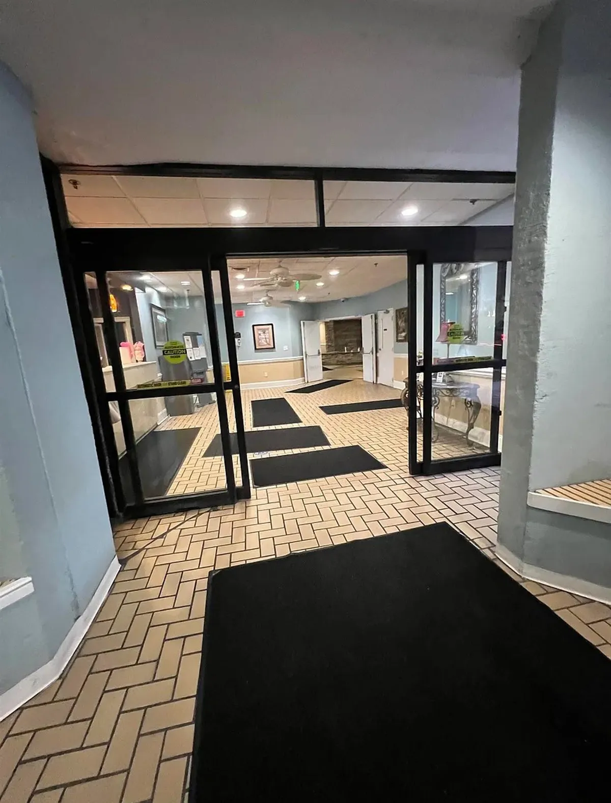 The image captures the property's glass entrance doors, a welcoming reception area, striking decorative wall art, and patterned flooring. The scene conveys the experience of arriving or returning after a fun-filled day, emphasizing hospitality and a sense of anticipation for the adventures ahead.